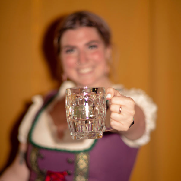 A woman in German clothing holding a Candid branded stein.